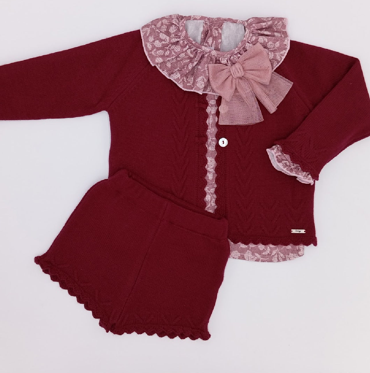 Maroon baby outfit with lace details and a bow on a white background
